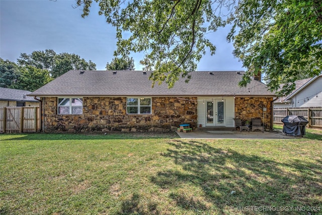 back of house with a patio, a fenced backyard, french doors, stone siding, and a lawn