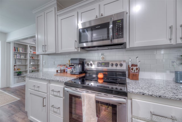 kitchen featuring appliances with stainless steel finishes, wood-type flooring, light stone counters, and white cabinets