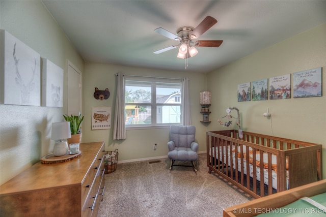 carpeted bedroom featuring ceiling fan and a crib