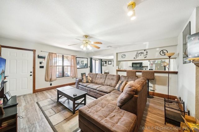 living room with a textured ceiling, ceiling fan, and light hardwood / wood-style floors