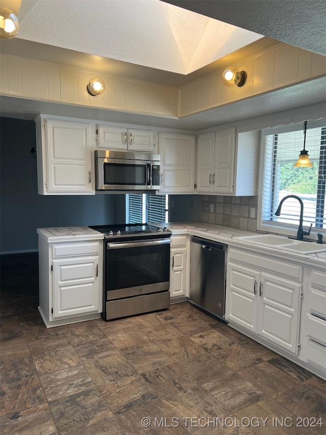 kitchen with appliances with stainless steel finishes, white cabinetry, and sink