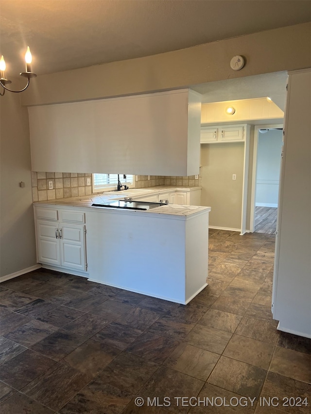 kitchen with kitchen peninsula, backsplash, and white cabinets