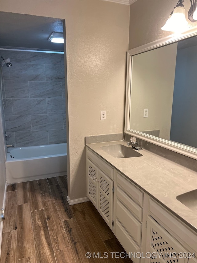 bathroom with tiled shower / bath combo, vanity, and wood-type flooring