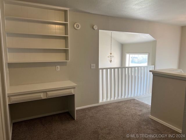 interior space featuring a textured ceiling and dark colored carpet