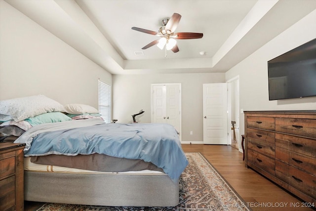 bedroom with a raised ceiling, ceiling fan, and hardwood / wood-style flooring