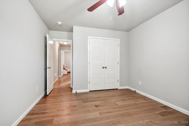 unfurnished bedroom with ceiling fan, light wood-type flooring, and a closet