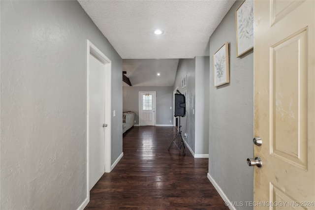 hallway featuring dark wood-type flooring, lofted ceiling, and a textured ceiling