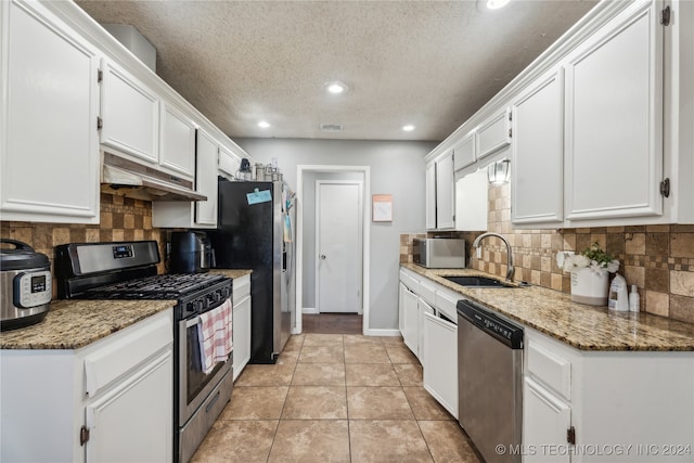 kitchen with dark stone countertops, white cabinetry, stainless steel appliances, and sink