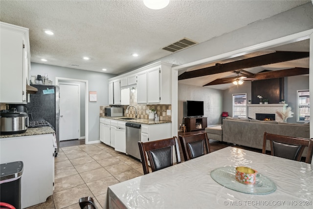 dining space featuring beamed ceiling, a textured ceiling, sink, ceiling fan, and light tile patterned flooring