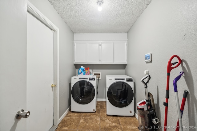 laundry room featuring a textured ceiling, cabinets, and washing machine and dryer