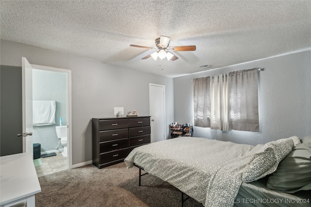 bedroom with a textured ceiling, ceiling fan, light carpet, and connected bathroom