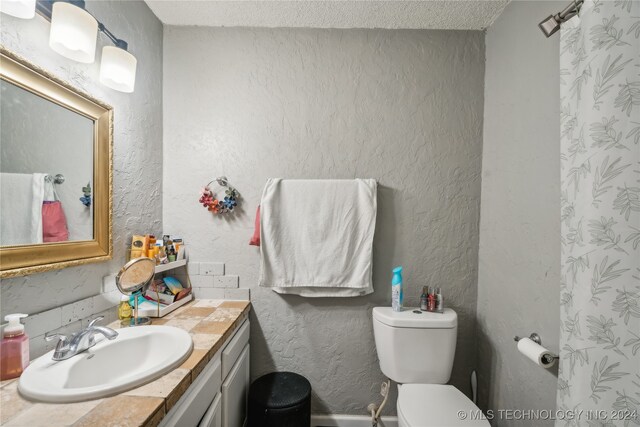 bathroom featuring a textured ceiling, vanity, and toilet