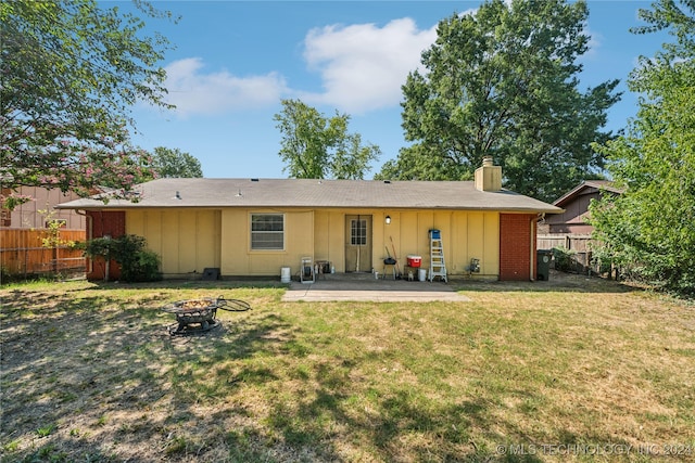 back of house with an outdoor fire pit, a patio area, and a lawn