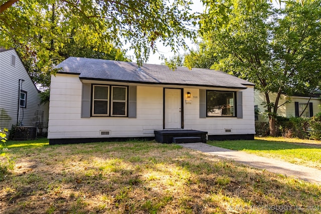 view of front of property with a front yard and central AC unit