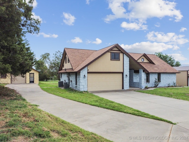 view of front of house featuring central air condition unit, a front lawn, and a garage