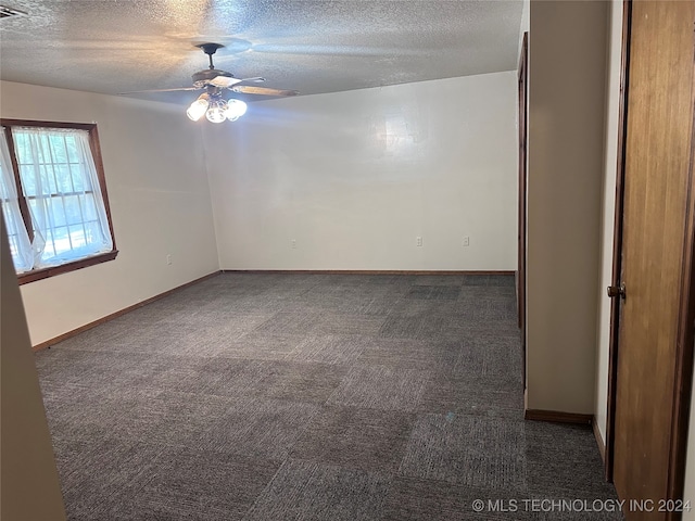 spare room with ceiling fan, a textured ceiling, and dark colored carpet