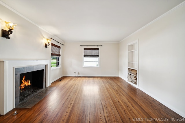 unfurnished living room with built in features, wood-type flooring, a fireplace, and ornamental molding