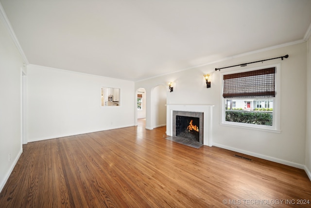 unfurnished living room with a fireplace, crown molding, and light hardwood / wood-style flooring