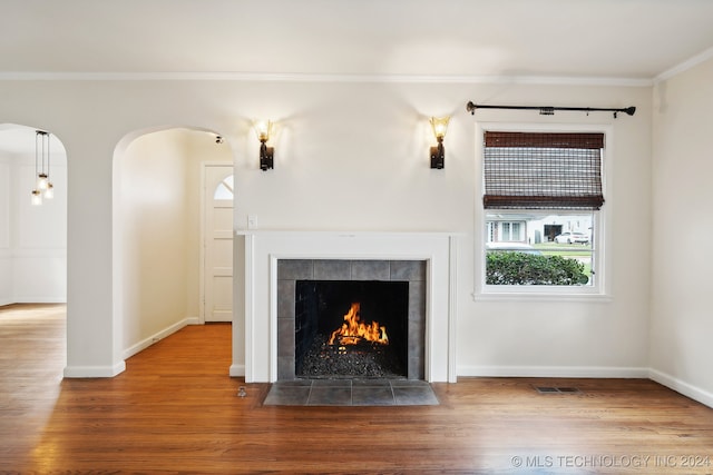 unfurnished living room with crown molding, wood-type flooring, and a fireplace