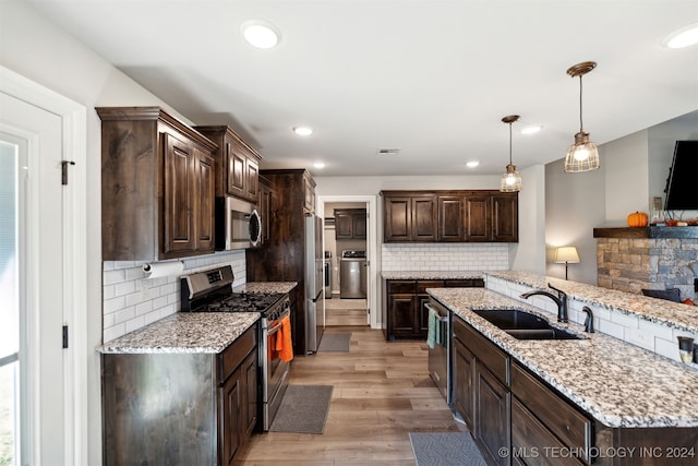 kitchen with stainless steel appliances, dark brown cabinets, light hardwood / wood-style flooring, decorative light fixtures, and sink