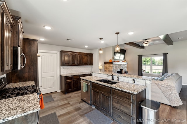 kitchen with a stone fireplace, hardwood / wood-style floors, ceiling fan, and stainless steel appliances