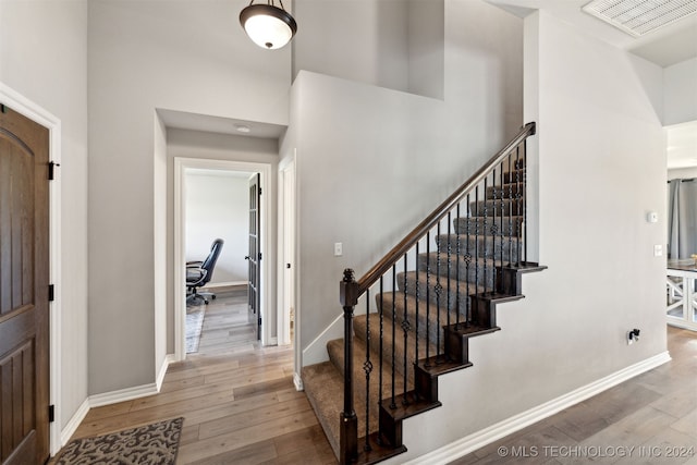 interior space with a towering ceiling and hardwood / wood-style flooring