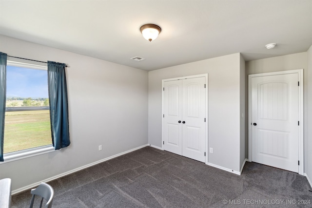 unfurnished bedroom featuring dark colored carpet and a closet