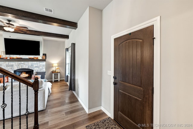 foyer entrance with ceiling fan, beamed ceiling, hardwood / wood-style flooring, and a fireplace