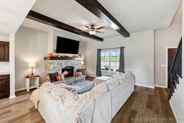 living room with beam ceiling, light hardwood / wood-style floors, ceiling fan, and a fireplace