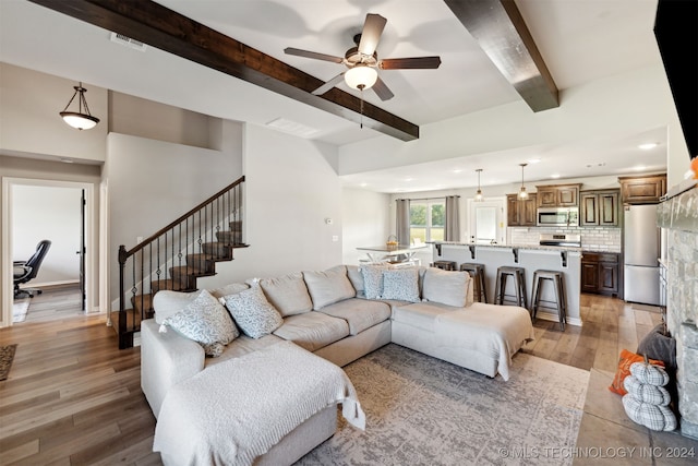 living room featuring ceiling fan, light hardwood / wood-style flooring, and beam ceiling