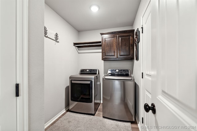 washroom featuring light hardwood / wood-style flooring, independent washer and dryer, and cabinets