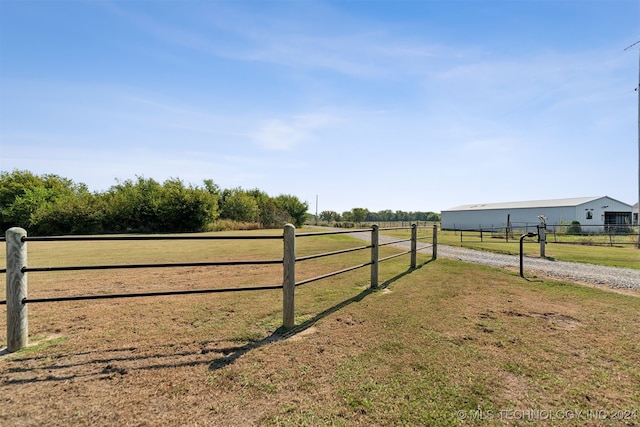 view of gate with a rural view and a lawn