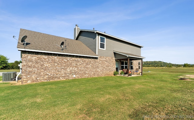 rear view of house with a patio area, central air condition unit, and a yard