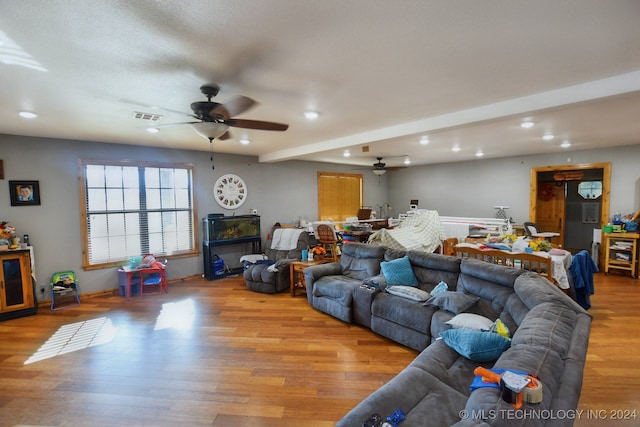 living room featuring light wood-type flooring, ceiling fan, beamed ceiling, and a textured ceiling