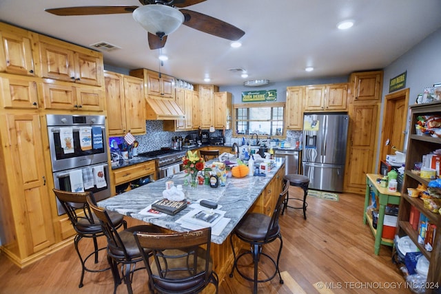 kitchen featuring light hardwood / wood-style flooring, backsplash, a center island, stainless steel appliances, and ceiling fan