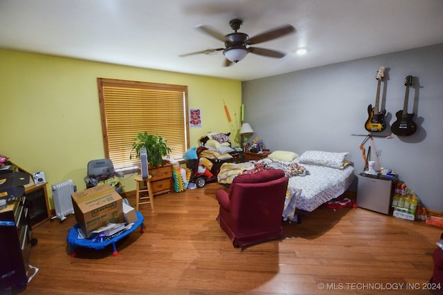 bedroom with hardwood / wood-style floors, ceiling fan, and radiator heating unit