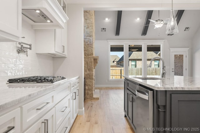 kitchen featuring appliances with stainless steel finishes, a sink, visible vents, and custom range hood