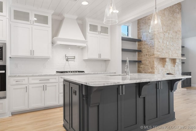 kitchen with premium range hood, white cabinetry, open shelves, tasteful backsplash, and cooktop