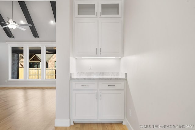 interior space with baseboards, glass insert cabinets, light wood-style flooring, and white cabinets