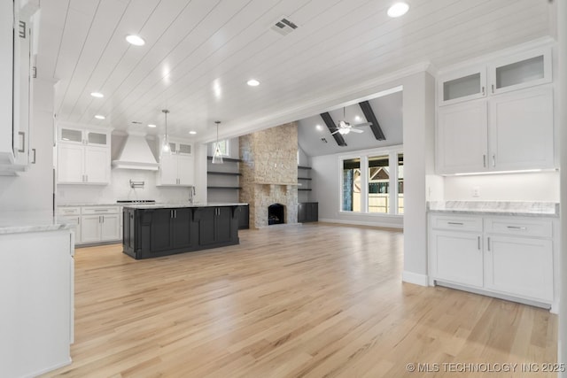 kitchen featuring vaulted ceiling with beams, open floor plan, white cabinetry, light wood-type flooring, and premium range hood