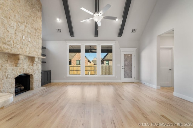 unfurnished living room with a ceiling fan, a stone fireplace, wood finished floors, beamed ceiling, and baseboards