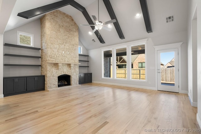 unfurnished living room featuring visible vents, a stone fireplace, light wood-type flooring, beamed ceiling, and baseboards