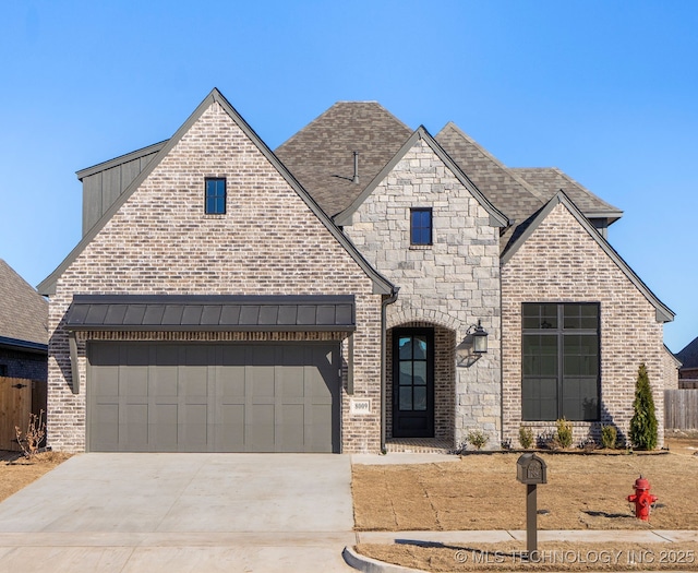 french country style house featuring driveway, fence, and brick siding