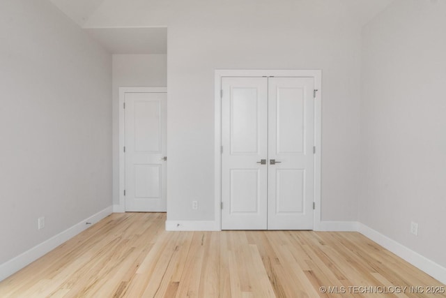 unfurnished bedroom with a closet, light wood-style flooring, and baseboards