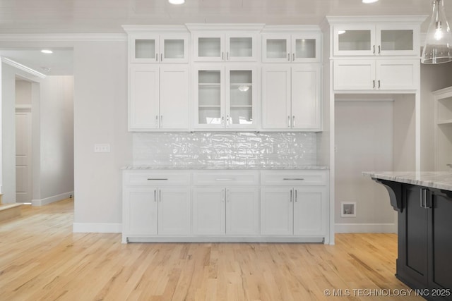 kitchen featuring light wood finished floors, baseboards, white cabinets, decorative backsplash, and light stone counters