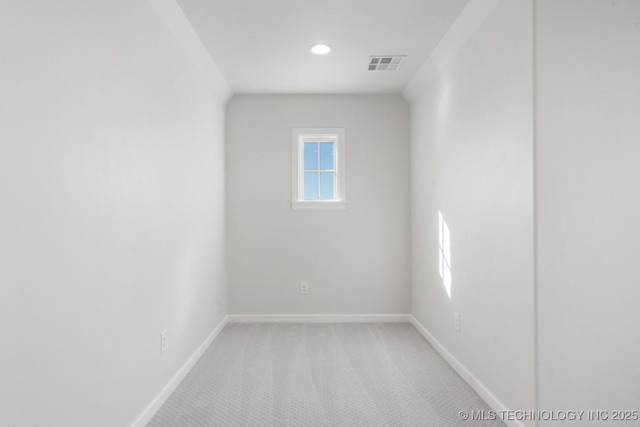 spare room featuring baseboards, visible vents, and light colored carpet