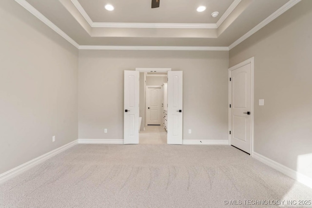 unfurnished bedroom with a tray ceiling, crown molding, and light colored carpet