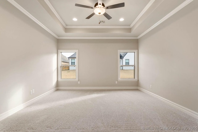 carpeted spare room featuring a tray ceiling, ceiling fan, and crown molding