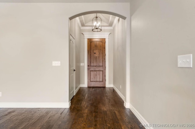 interior space with a notable chandelier, dark hardwood / wood-style floors, crown molding, and a tray ceiling