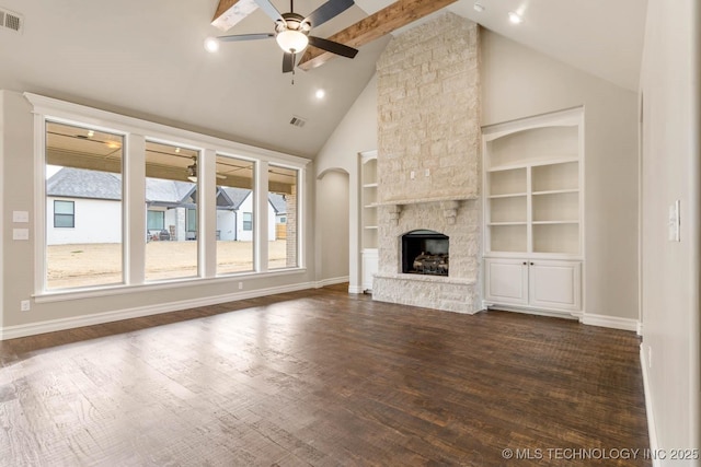 unfurnished living room with a stone fireplace, ceiling fan, dark hardwood / wood-style floors, built in features, and beamed ceiling